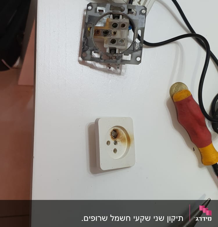 שקע חשמלי מפורק עם כלי עבודה על שולחן